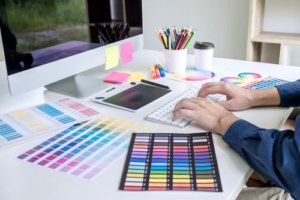 色見本を見ながらパソコンでデザインを制作する様子