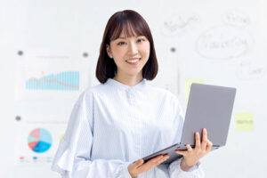 ノートパソコンを持って説明する女性